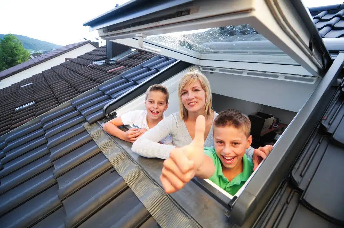 Une famille sur une toiture dans les deux sèvres regarde par un velux